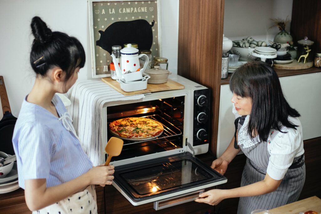 Women cooking pizza in an oven